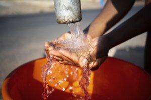 mujer africana vertiendo agua recipiente al aire libre 300x200 - Serie CSP